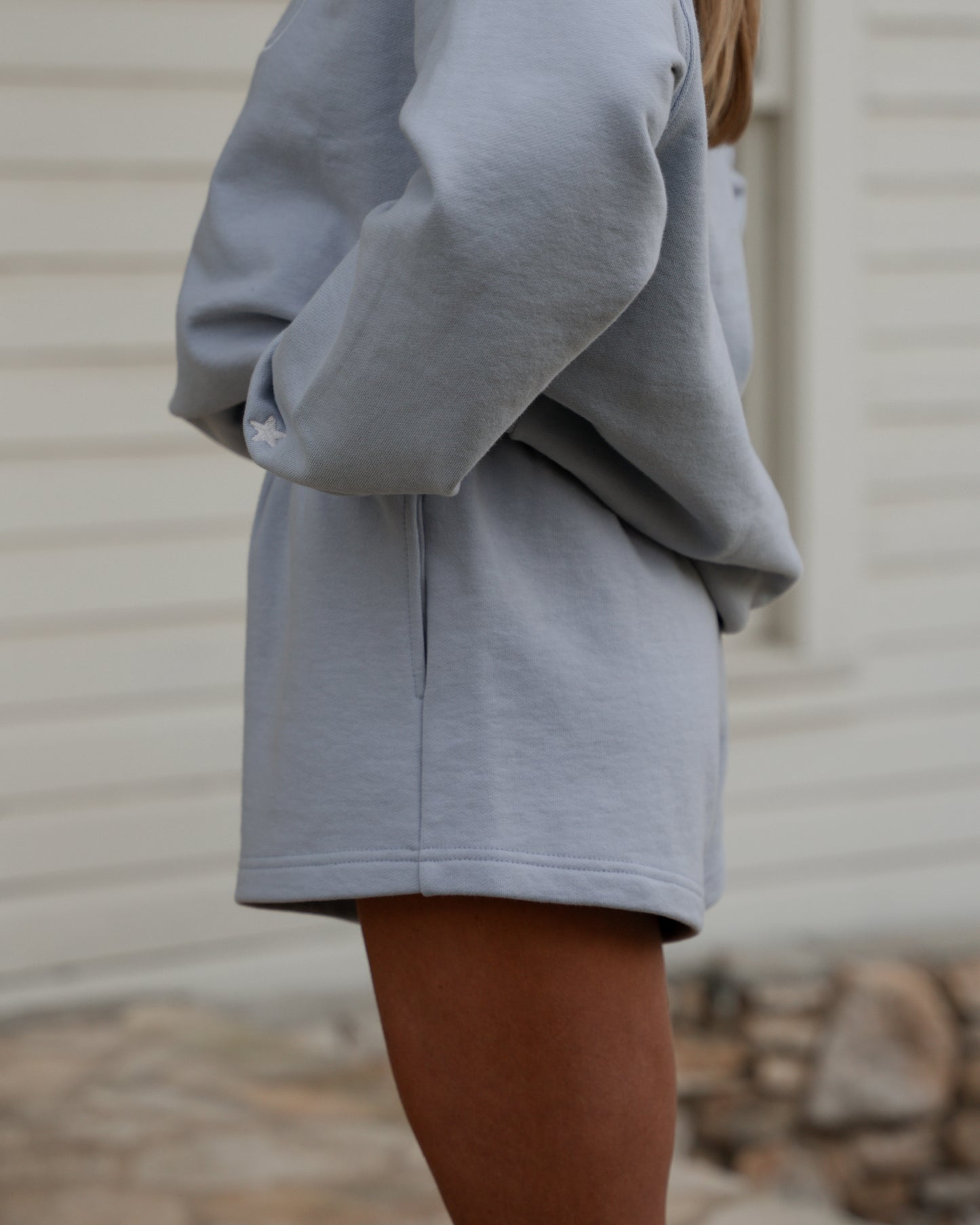 Person wearing a gray hoodie and skirt set with a neutral background