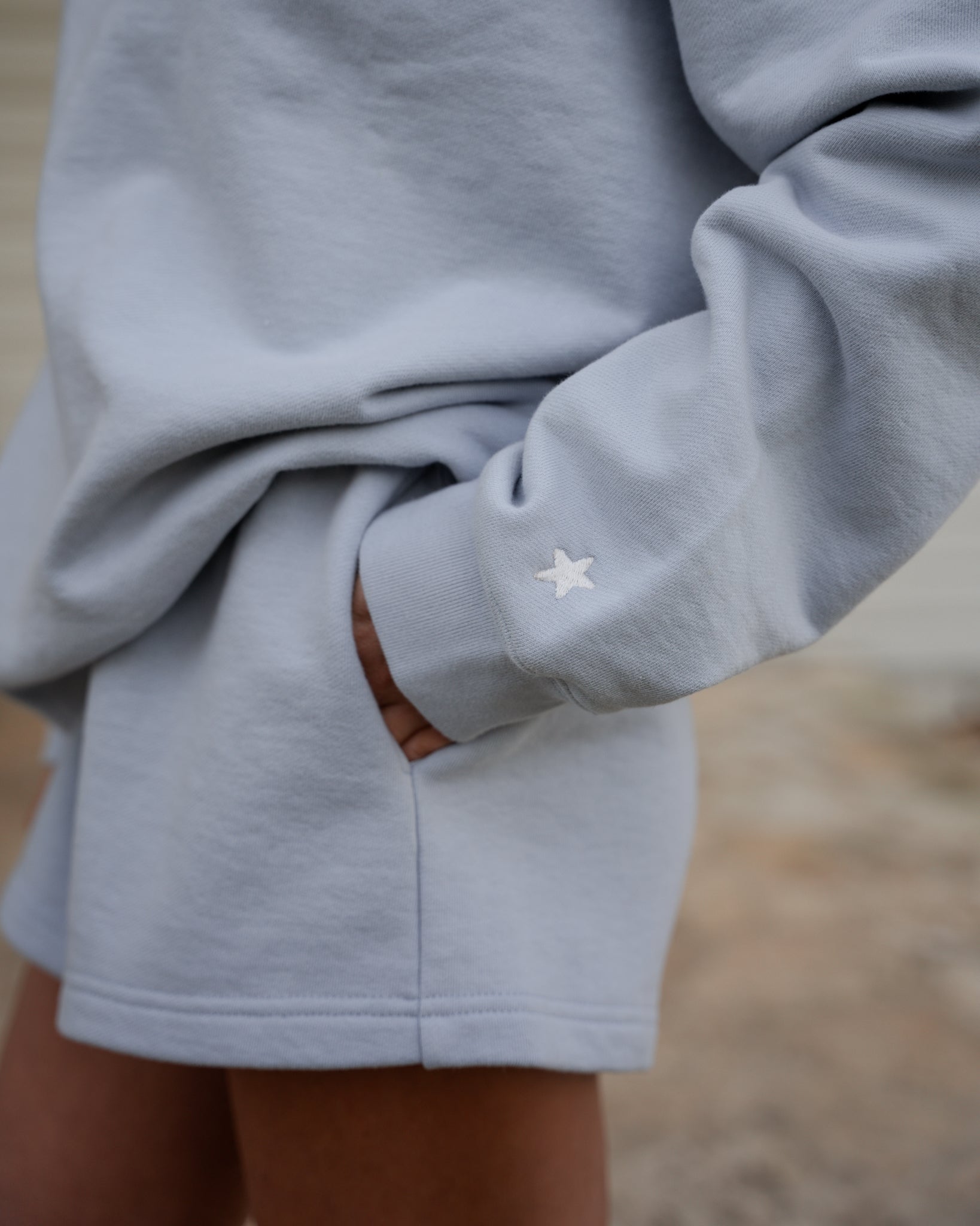 Gray sweatshirt with a star detail on the sleeve against a blurred background