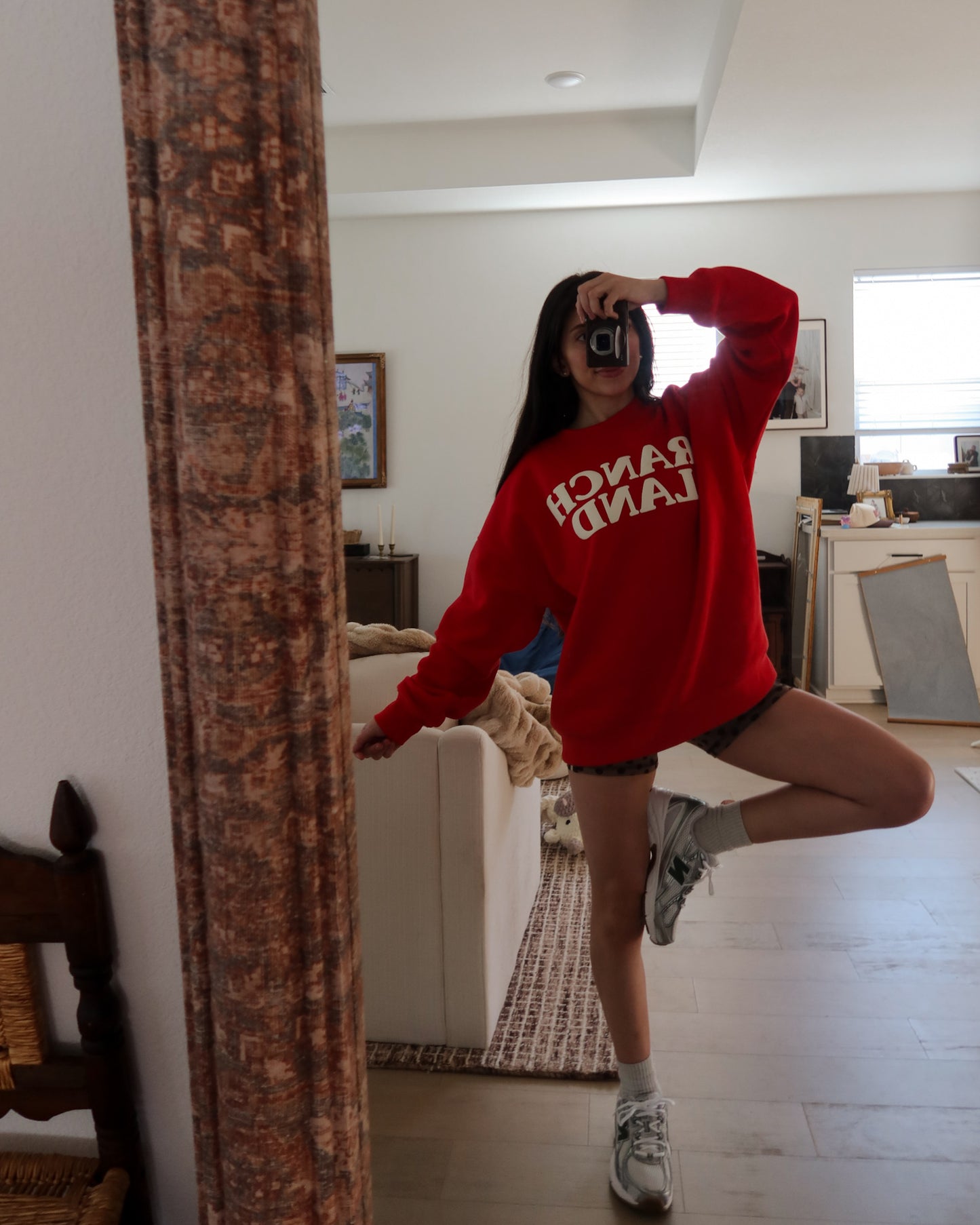 Person wearing a red sweatshirt with text, posing in a room.